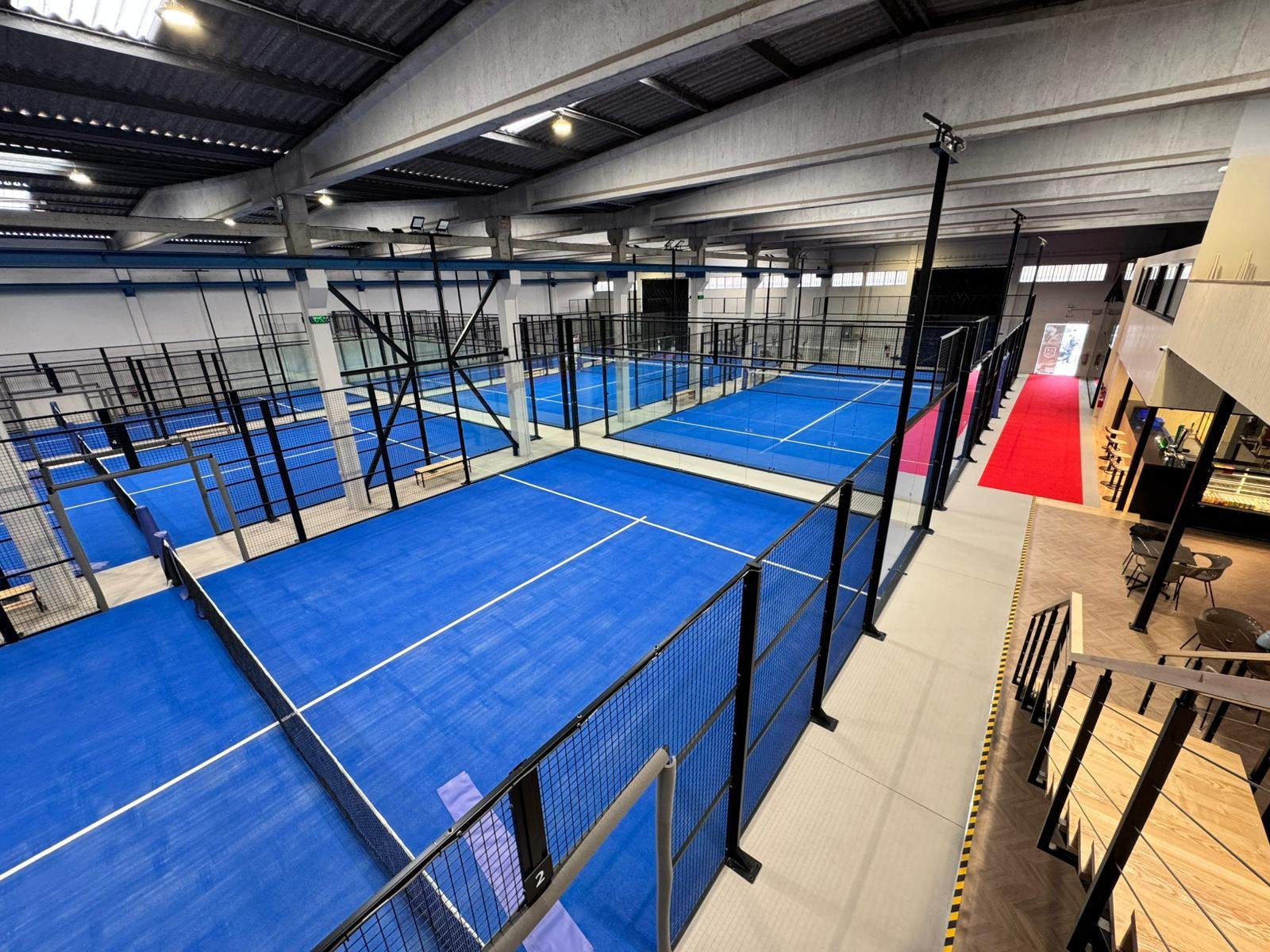 Pista de tênis de mesa em uma quadra coberta em ambiente de academia ou centro esportivo.